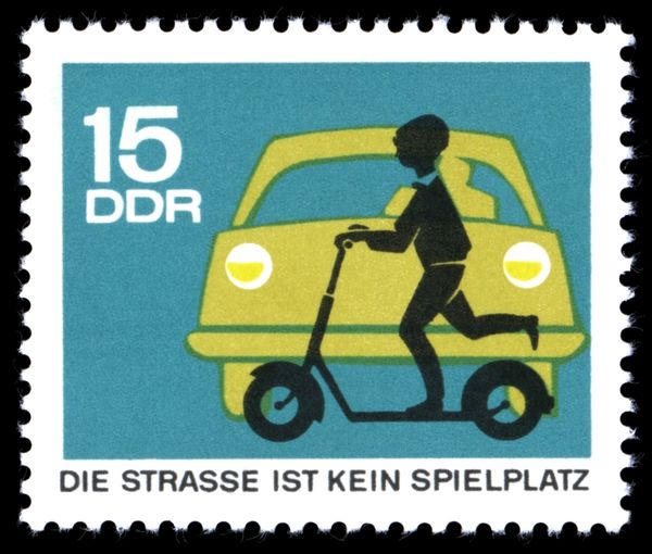 Child with a scooter before cars
