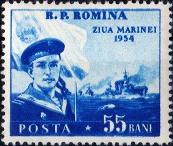 Sailor in front of flag & warships
