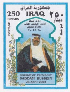 Saddam with a white head scarf and a black cape