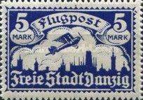 Airplane flying over the silhouette of the skyline of Danzig