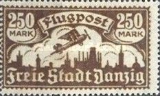 Airplane flying over the silhouette of the skyline of Danzig