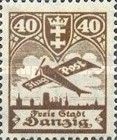 Airplane flying over the silhouette of the skyline of Danzig