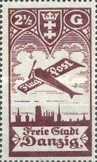 Airplane flying over the silhouette of the skyline of Danzig